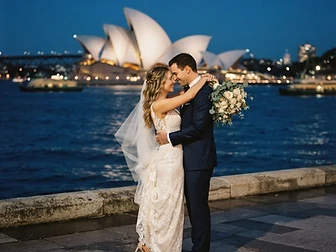 Sydney wedding photography — a couple embracing with the Sydney Opera House sails glowing at blue hour over Sydney Harbour