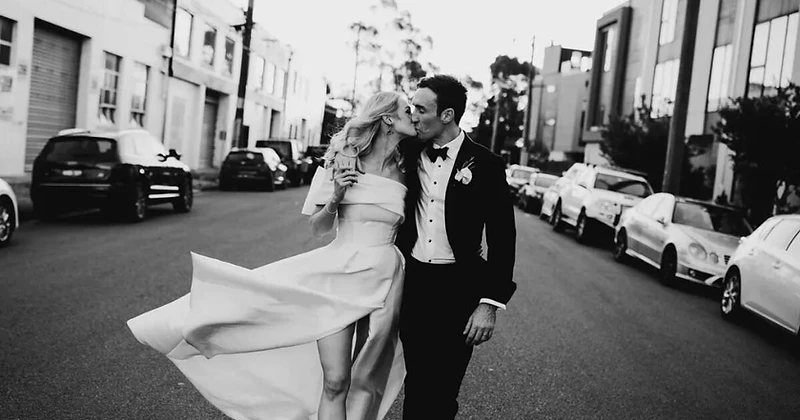 A bride and groom walking down an urban Sydney street together, captured in editorial black and white