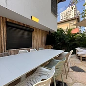 פינת אוכל חוץ עם שולחן, טלוויזיה ועמדת חימום בגינה מעוצבת