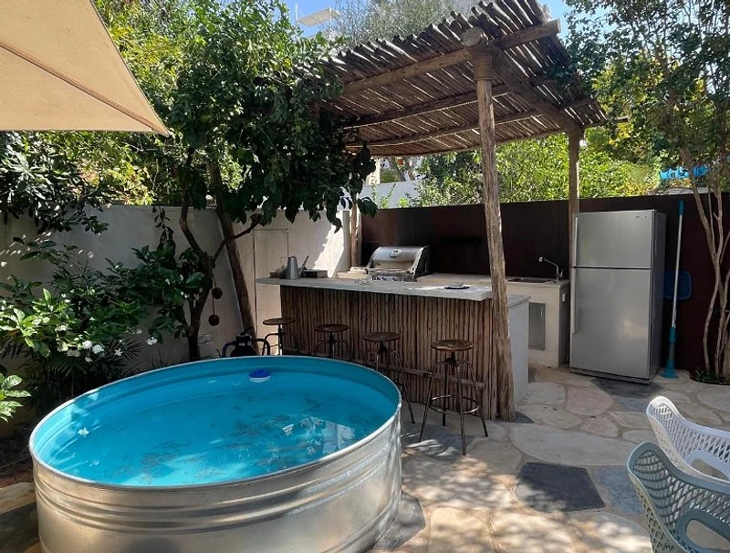 מטבח חוץ ופינת אירוח מעוצבת עם פרגולת עץ וברית פלדה באשדוד - פאפאיה נוף