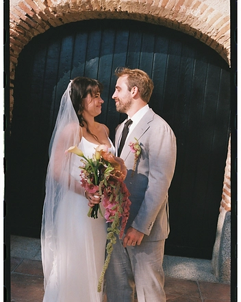 Bride and groom in front of an arched wooden door