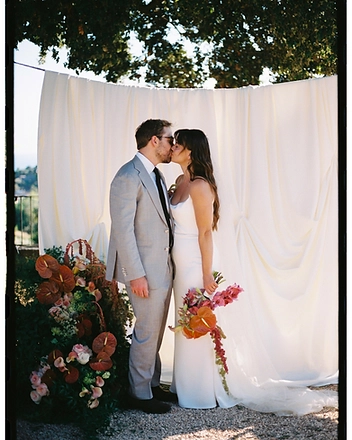 Bride and groom kissing beside the floral arrangement