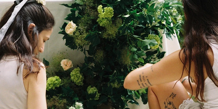 Abundant floral installation alongside a sweetheart table with a white draped backdrop