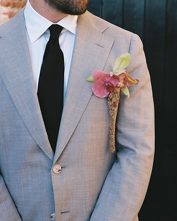 Boutonniere of orchid and amaranth on a grey lapel