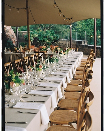 Long banquet table beneath marquee string lights
