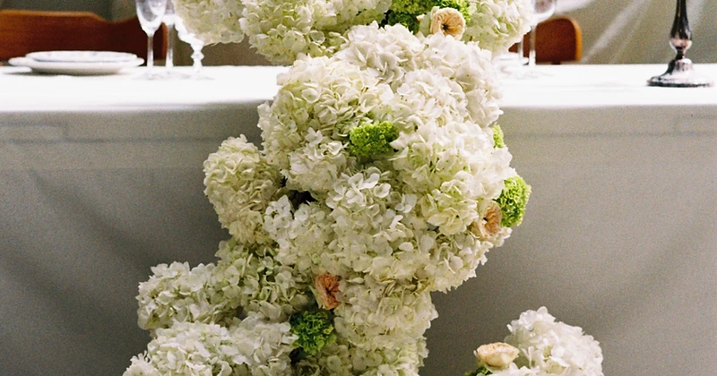 White hydrangea floral installation beside a candlelit sweetheart table