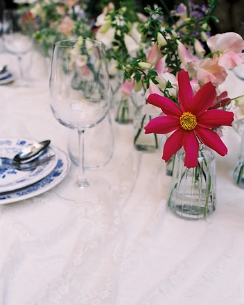 Detail of foxglove and daisy bud vases on linen tablecloth
