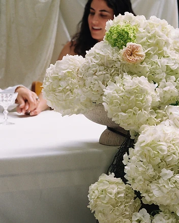 White hydrangea column with laughing guests in background