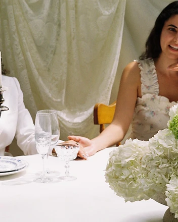 Couple at sweetheart table framed by white hydrangea installation
