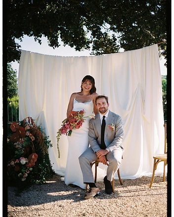 Bride and groom seated on wooden chairs