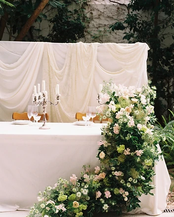 Full view of draped sweetheart table with floral installation