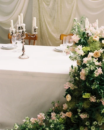 Full outdoor sweetheart table with draped backdrop and florals