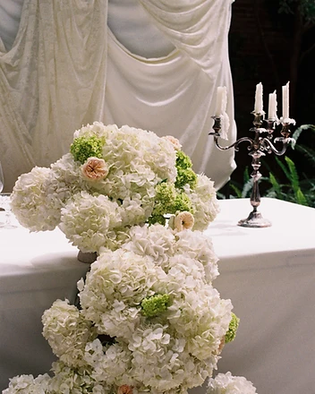 Guest smiling behind oversized white and green hydrangea arrangement