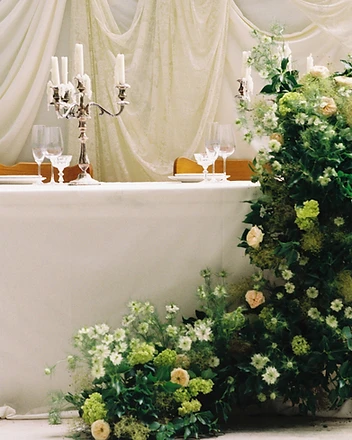 Sweetheart table with lush green and ivory floor installation