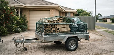 A plain unbranded trailer on a driveway with a securely netted load of rubbish and timber