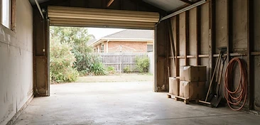 An emptied residential garage with a swept concrete floor and the roller door open