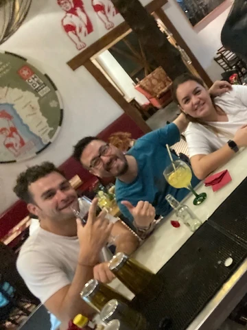 Friends at a bar counter in Chile, peace signs and thumbs up