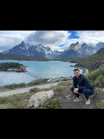 Hiker overlooking a turquoise glacial lake and mountains