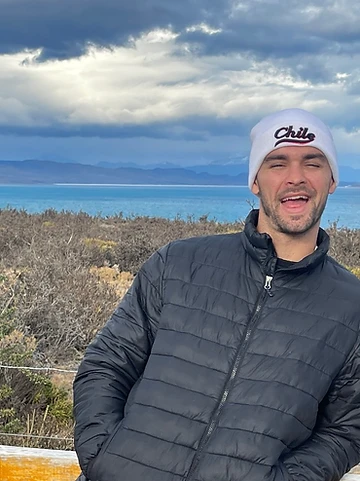 Smiling in a Chile beanie against a turquoise lake and mountains
