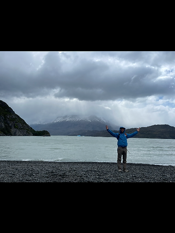 Hiker with arms outstretched beside a Patagonian lake