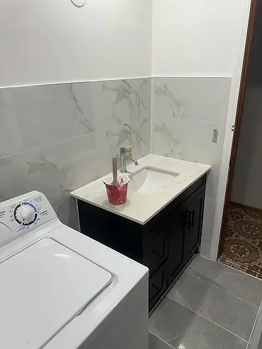 Black bathroom vanity with white countertop, chrome faucet and marble-look tile backsplash