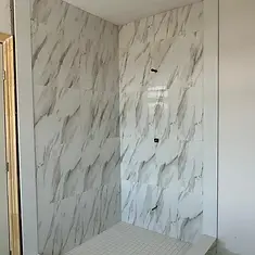 New marble-look tiled shower with mosaic floor during bathroom renovation