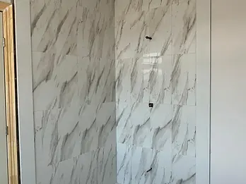 New marble-look tiled shower with mosaic floor during bathroom renovation