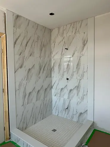 New marble-look tiled shower with mosaic floor during bathroom renovation