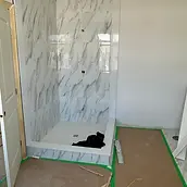 Marble-look tiled shower and protected bathroom floor during renovation