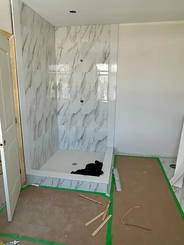Marble-look tiled shower and protected bathroom floor during renovation
