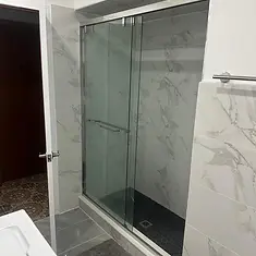 Finished sliding glass shower enclosure with marble-look tile and dark mosaic floor