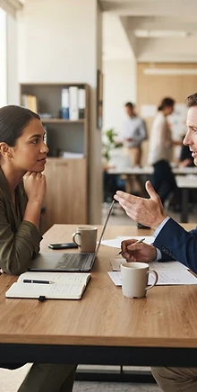 Two professionals in attentive conversation in a bright modern office