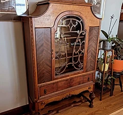 Antique wooden china cabinet with ornate top