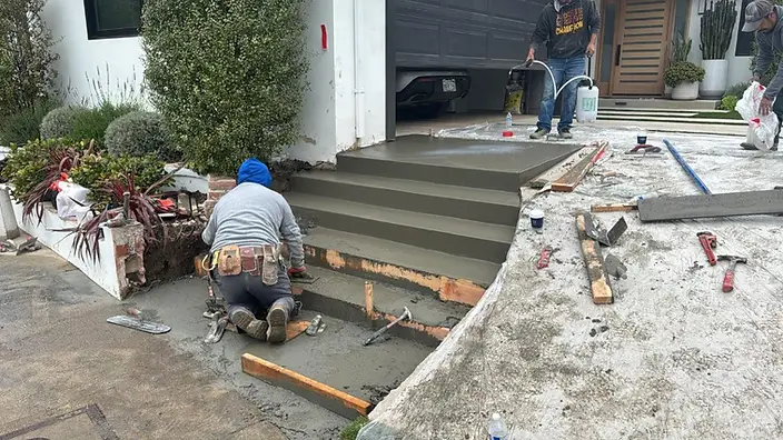 Concrete finisher troweling freshly poured entry steps at a modern Los Angeles home