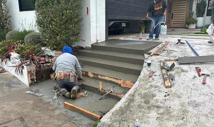 Concrete finisher troweling freshly poured entry steps at a modern Los Angeles home