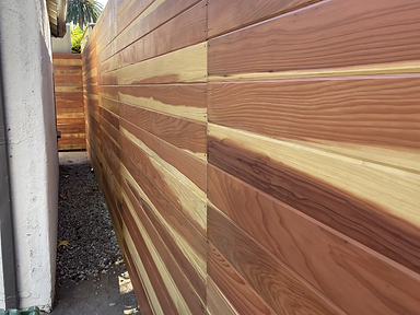 Close angled view of a horizontal cedar wood privacy fence showing varied wood grain tones