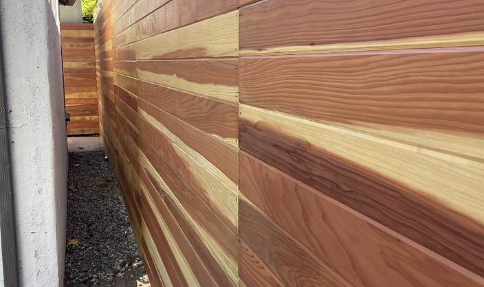 Close angled view of a horizontal cedar wood privacy fence showing varied wood grain tones
