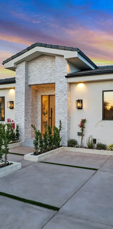 Single story home with stone entryway and concrete driveway at twilight.