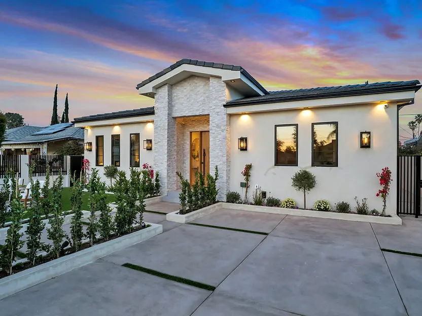 Single story home with stone entryway and concrete driveway at twilight.