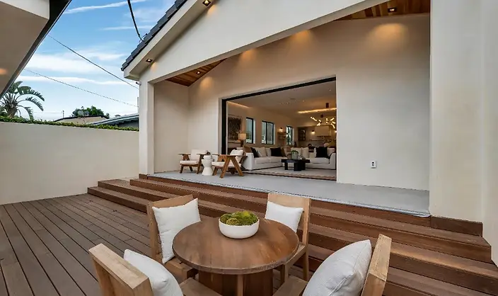 Hardwood deck with an outdoor dining set at a Valley Glen project, showing indoor-outdoor flow through large sliding doors.