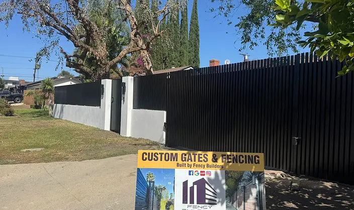Black steel vertical slat fence with stucco base wall — fence and gate installation by Fency Builders in Hollywood, Los Angeles.