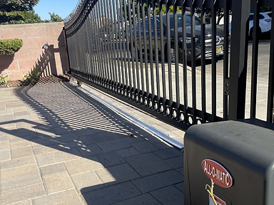 Black ornamental wrought iron sliding driveway gate with decorative finials and automatic opener