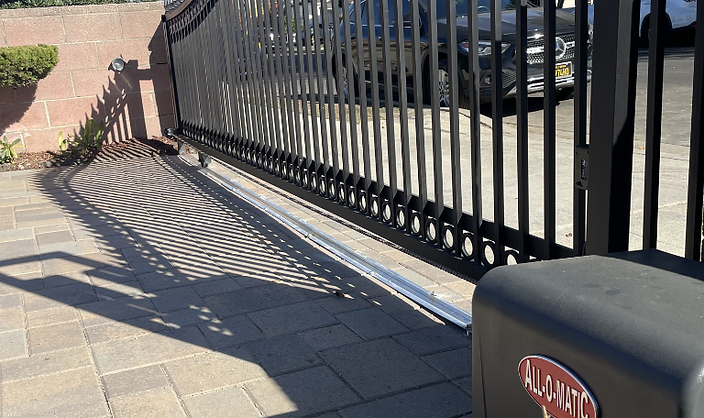 Black ornamental wrought iron sliding driveway gate with decorative finials and automatic opener