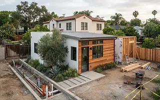 Editorial illustration: Detached modern ADU under construction in a Los Angeles backyard with an open utility trench alongside