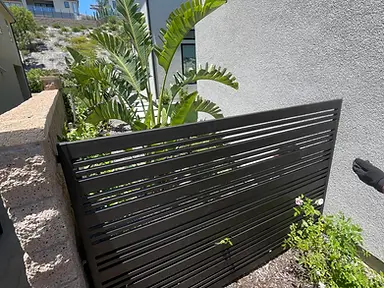 A natural cedar board-on-board privacy fence runs along a residential side yard with grass at its base.