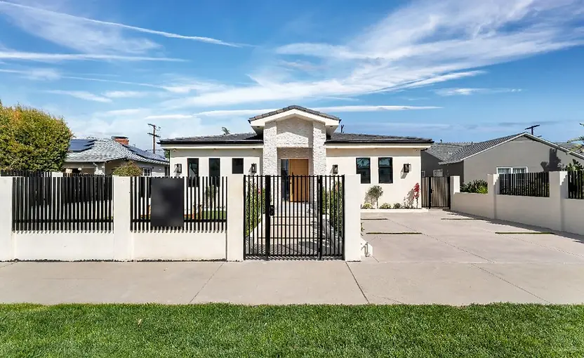 Completed New Construction home in Valley Glen with a light stucco facade, stone entry, landscaping, and black metal gate.