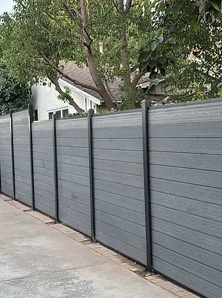 A completed gray composite privacy fence with black metal posts.