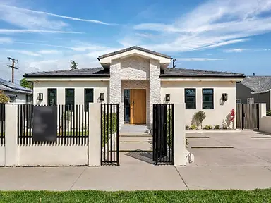 Front entrance of a completed New Construction home in Valley Glen viewed through the black metal entry gate.