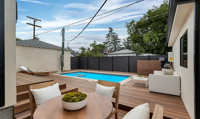 Wide-angle view of IPE deck, pool, lounge chairs, and dark privacy fence at new-construction Valley Glen, Los Angeles home.