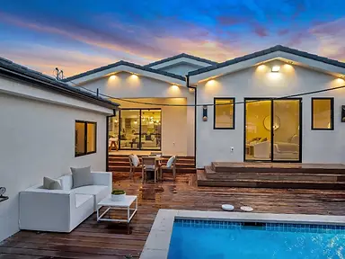 Completed New Construction home in Valley Glen with a rear deck, sliding doors, and pool at sunset.